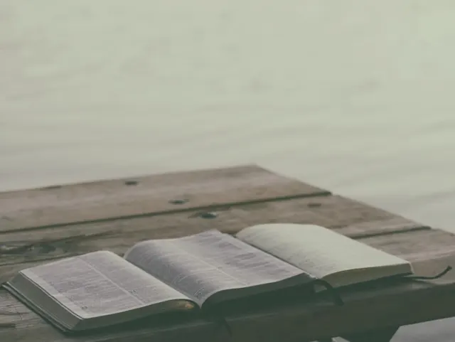 Open Bible on a wooden dock by the water